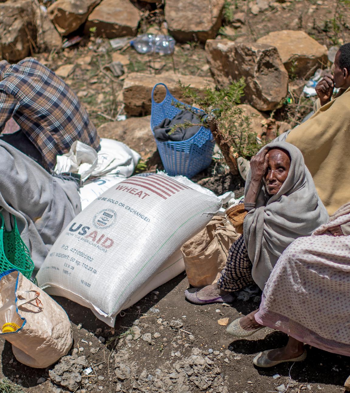 Eine ältere äthiopische Frau sitzt neben einem Sack mit Weizen, nachdem dieser von der Relief Society of Tigray in der Region Tigray im Norden Äthiopiens verteilt wurde.