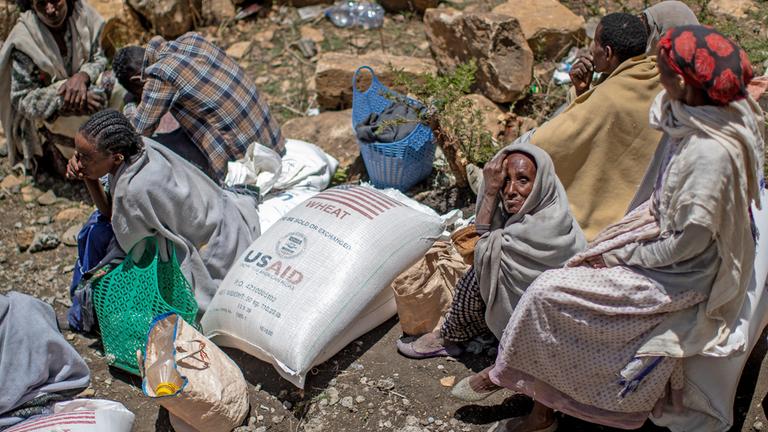 Eine ältere äthiopische Frau sitzt neben einem Sack mit Weizen, nachdem dieser von der Relief Society of Tigray in der Region Tigray im Norden Äthiopiens verteilt wurde.