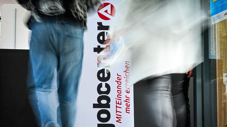 Berlin: Personen gehen am Logo vom Jobcenter Berlin-Mitte bei einer Jobmesse vorbei.
