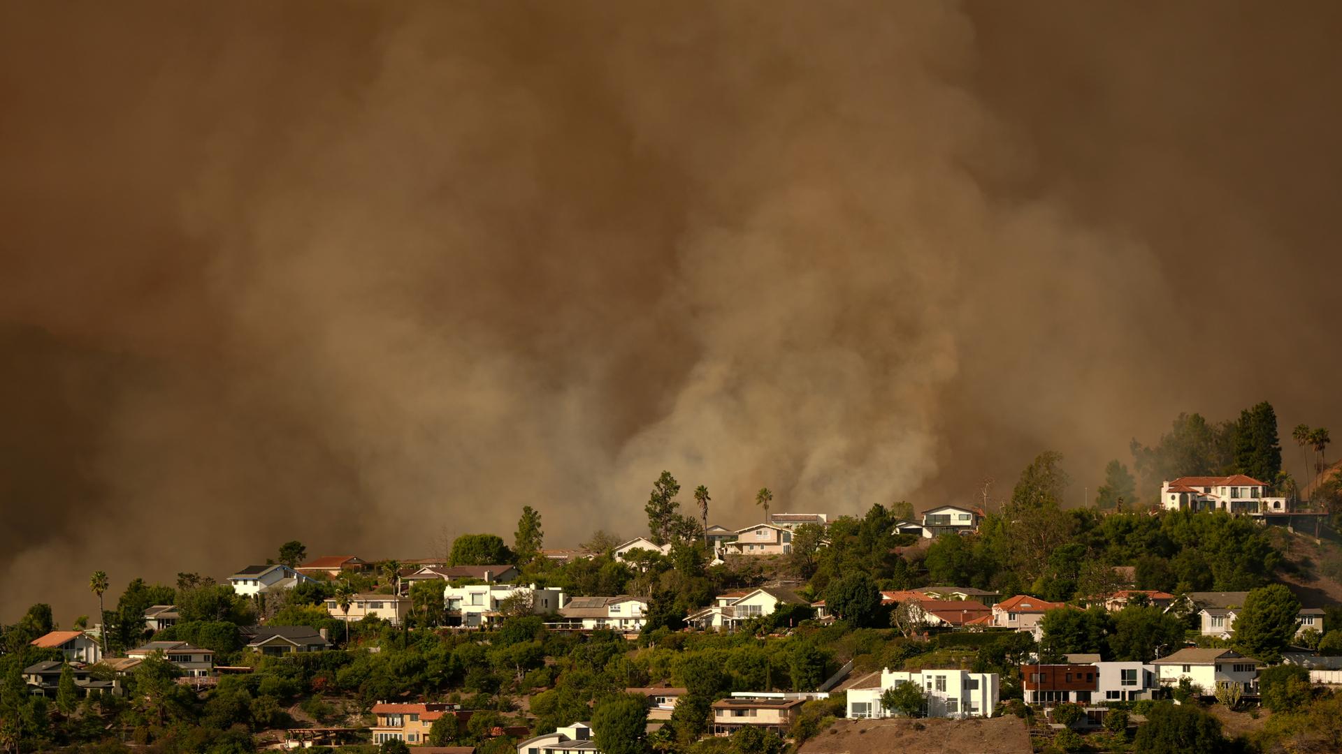 Der Rauch des Palisades-Feuers steigt in Los Angeles über Wohnhäusern im Mandeville Canyon auf. 