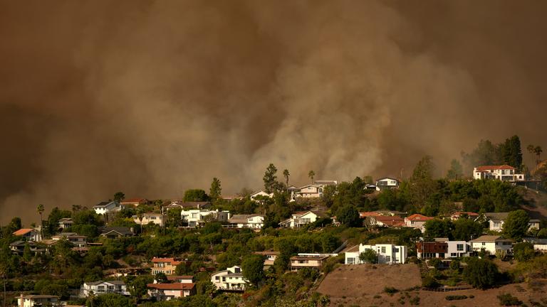 Der Rauch des Palisades-Feuers steigt in Los Angeles über Wohnhäusern im Mandeville Canyon auf. 