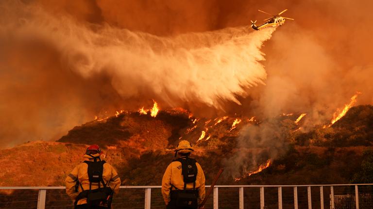 Los Angeles: Feuerwehrleute beobachten, wie Löschwasser auf das Palisades-Feuer im Mandeville Canyon Angeles geworfen wird