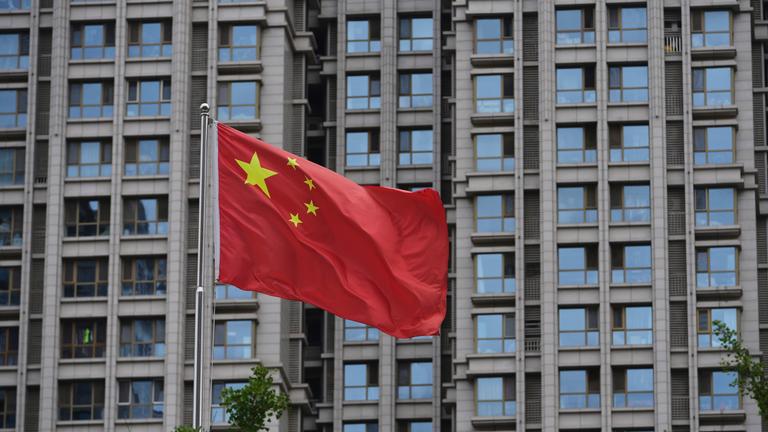 China, Peking: Eine chinesische Nationalflagge weht vor einem Wohngebäude in Peking