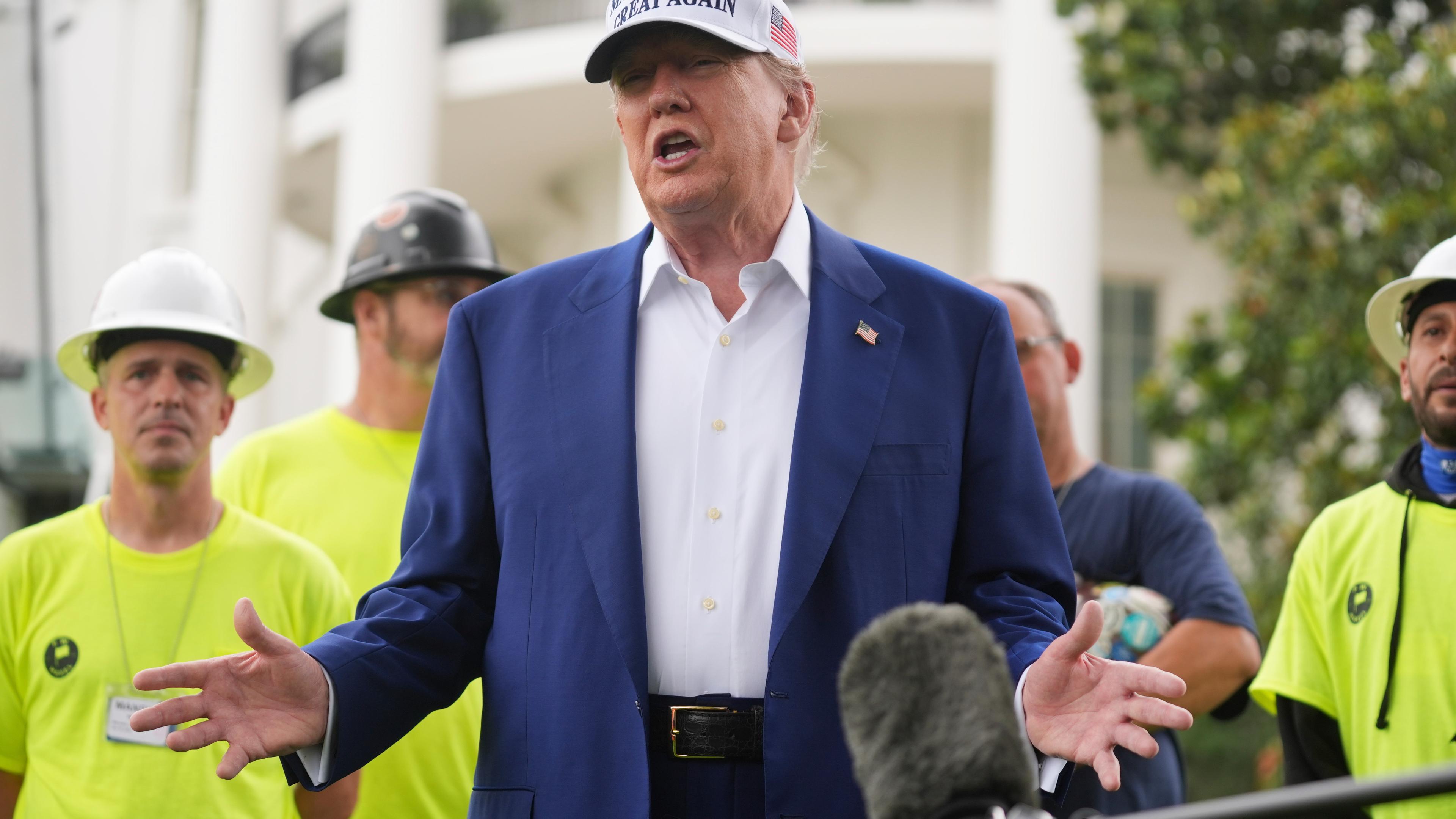 18.06.2025, USA, Washington: US-Präsident Donald Trump spricht zu Arbeitern, während ein Flaggenmast auf dem Südrasen des Weißen Hauses installiert wird.