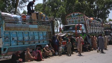 Afghanische Flüchtlingsfamilien, die auf dem Weg zurück in ihr Heimatland sind, versammeln sich neben Lastwagen in Pakistan am 25.08.2025