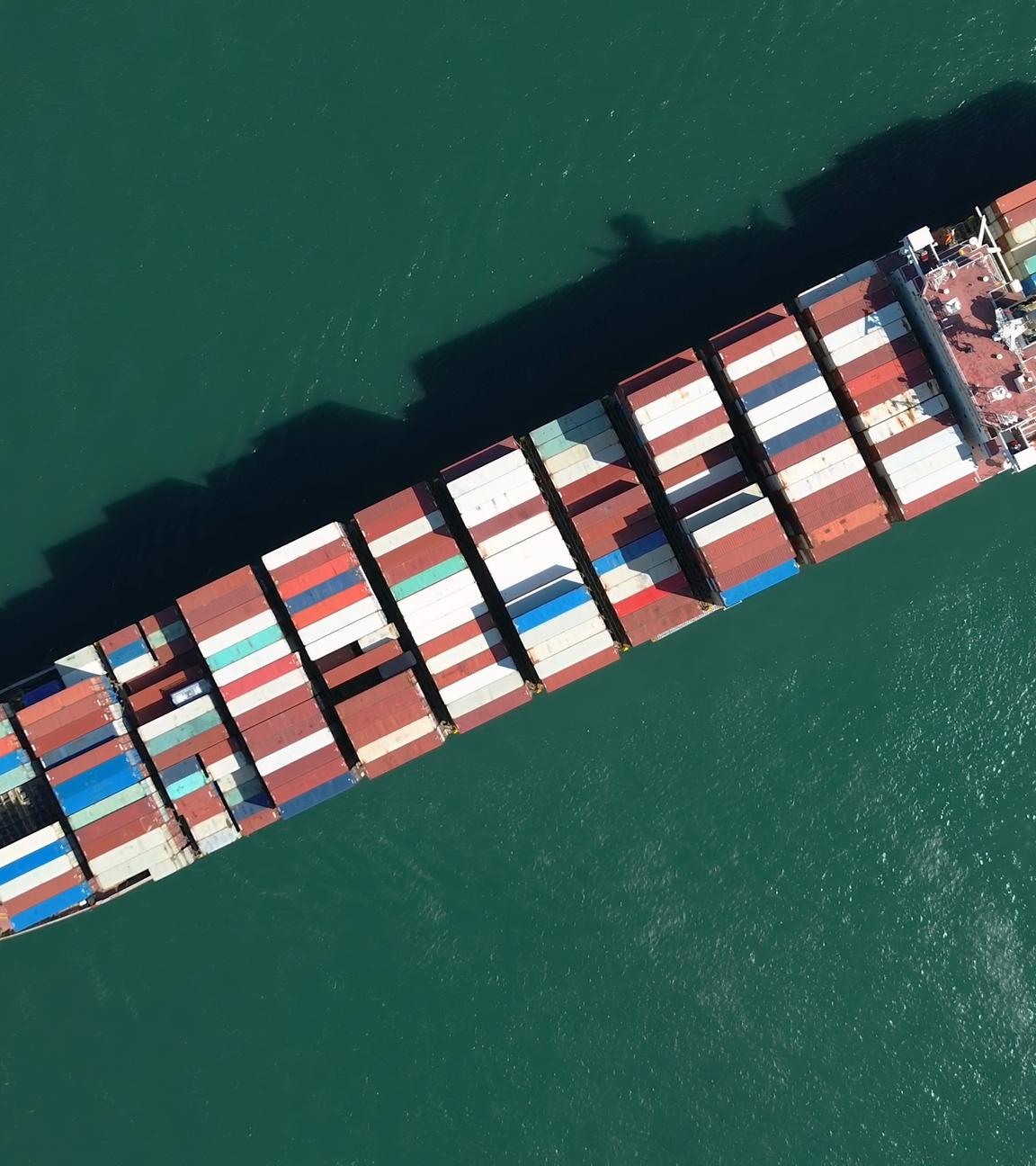 Draufsicht auf ein großes, mit bunten Containern gefülltes Frachtschiff; abschluss; anschluss; ausruestung; basspfeife; behälter; boot; bunten; container; containerhafen; containern; dock; draufsicht; draussen; fracht; frachtschiff; gefülltes; globalisierung; großes; hafen; handel; industrie; kommerziell; konjunktur; lieferkette; logistik; luftbildaufnahme; marin; marine; maritim; meer; navigation; ozean; schlepper; tag; top; transport; transportieren; umschlag; wachstum; wasserfahrzeug; wirtschaft; über