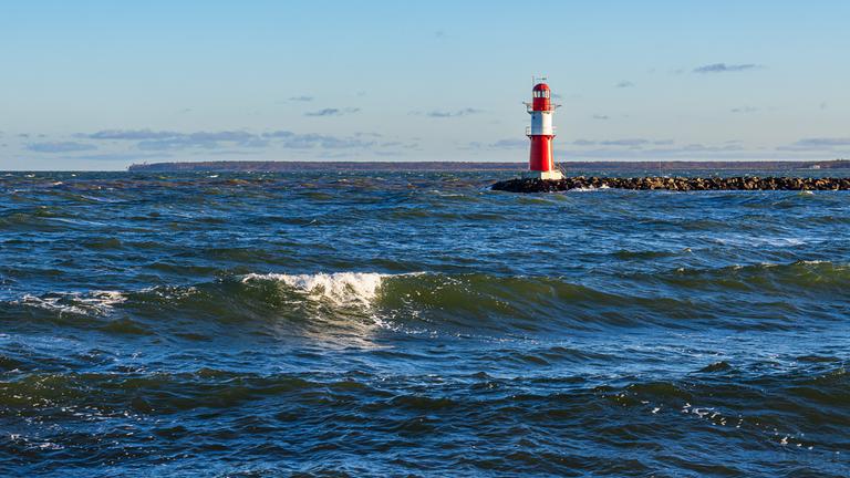 Wellen und Molenturm an der Küste der Ostsee in Warnemünde