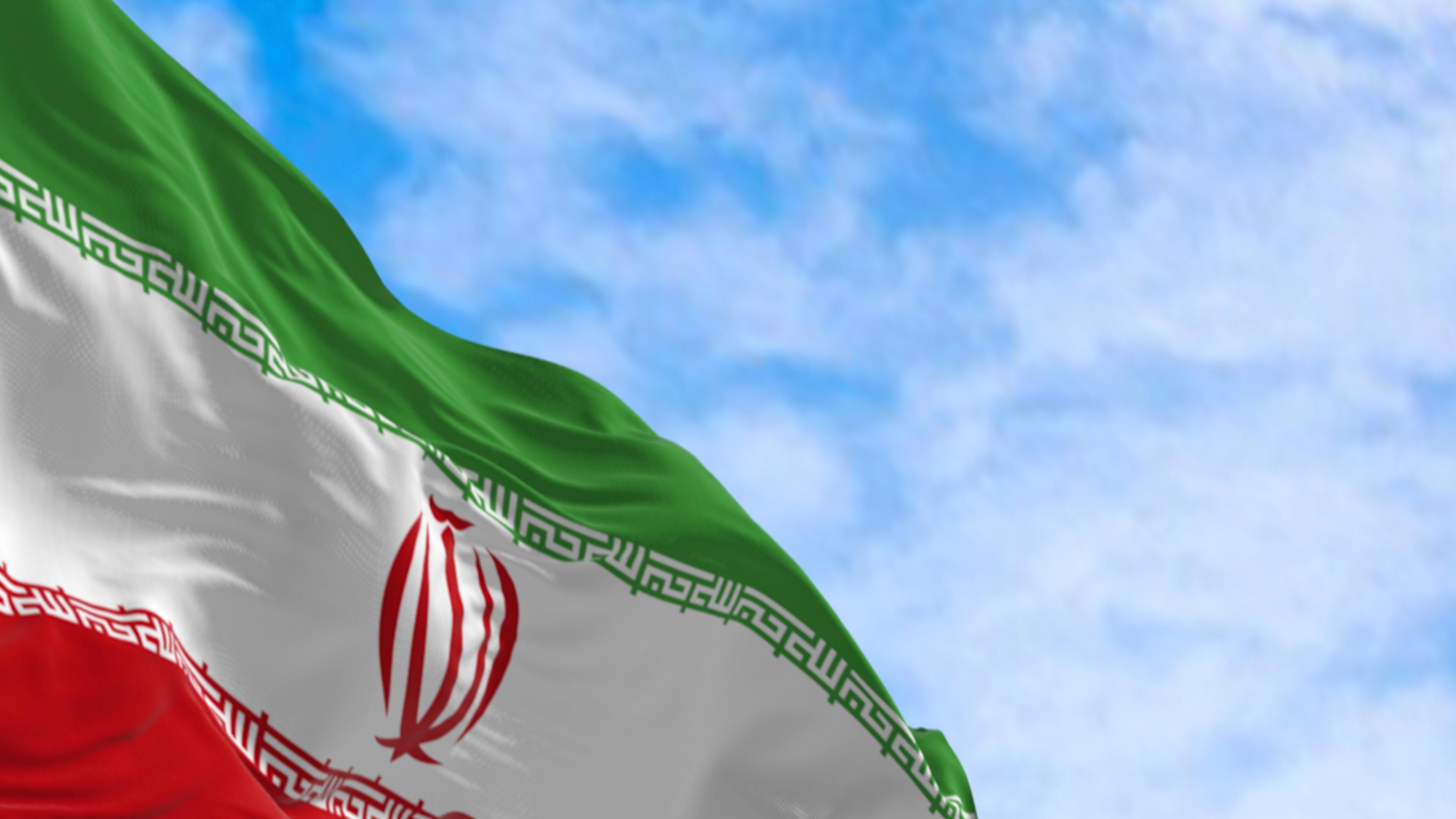 Islamische Republik Iran Nationale Flagge waving an einem klaren Tag. Horizontale Tricolor von grün, weiß und rot, rote nationale Emblem, weiße Takbir Text geschrieben in Kufic Skript.