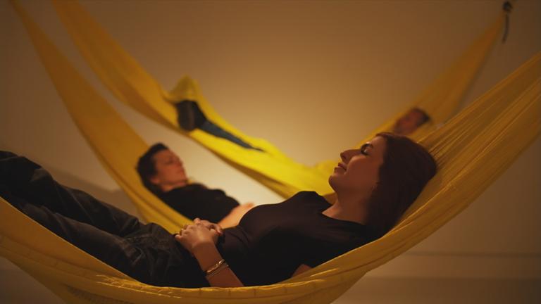 Drei Menschen liegen träumend auf drei Hängematten 