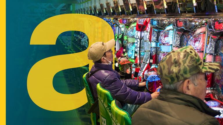 Alter Mann mit Schirmmütze sitzt vor Spielautomat in Japan