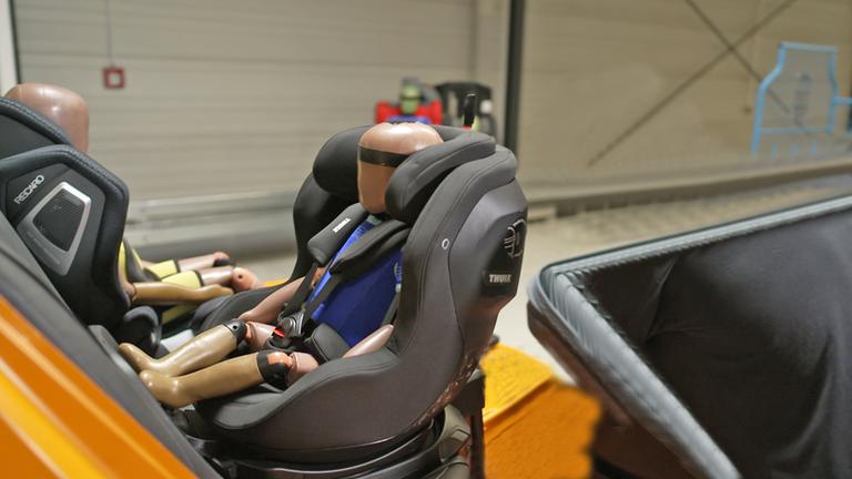 zwei Crashtest-Dummy-Kinder in einem Versuchsaufbau mit Kindersitzen