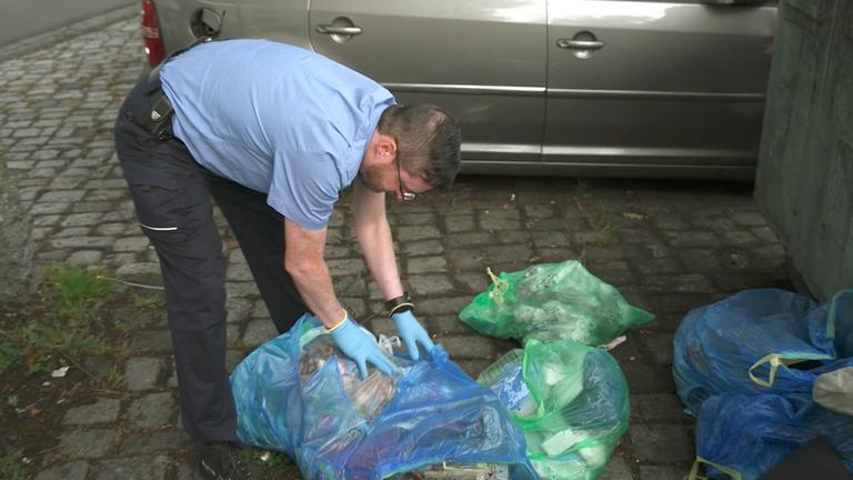 Mitarbeiter des Zentralen Kommunalen Entsorgungsbetriebs Saarbrücken durchsucht eine Mülltüte nach Informationen über die Person, die den Abfall illegal entsorgt hat