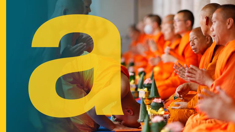 Mönche sitzen in orangenen Gewändern nebeneinander.