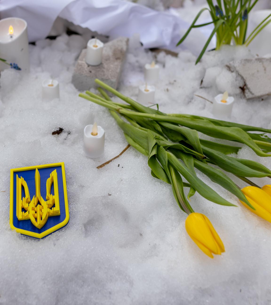 Blumen, Abzeichen und Kerzen als Gedenken an die Opfer auf die Ukraine