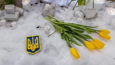 Blumen, Abzeichen und Kerzen als Gedenken an die Opfer auf die Ukraine