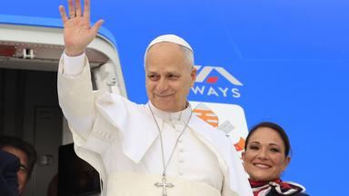 Papst Leo winkt in die Kamera vor einem Flugzeug