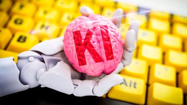 Roboterhand hält ein Gehirn mit Aufschrift KI vor Computertastatur, Symbolfoto Künstliche Intelligenz, Fotomontage