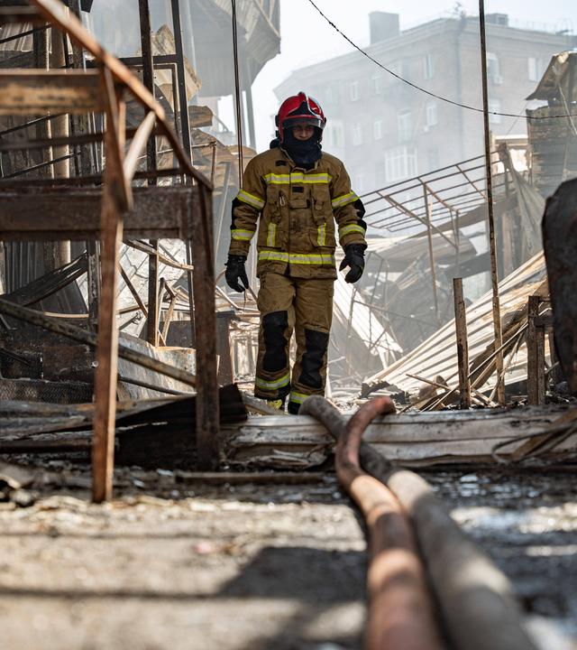 Ukrainischer Feuerwehrmann inmitten zestörter Gebäude