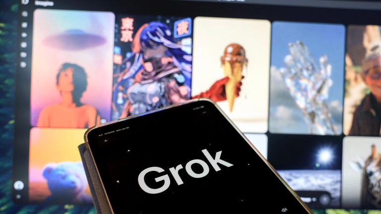 Grok auf dem Handy vor dem Laptopbildschirm