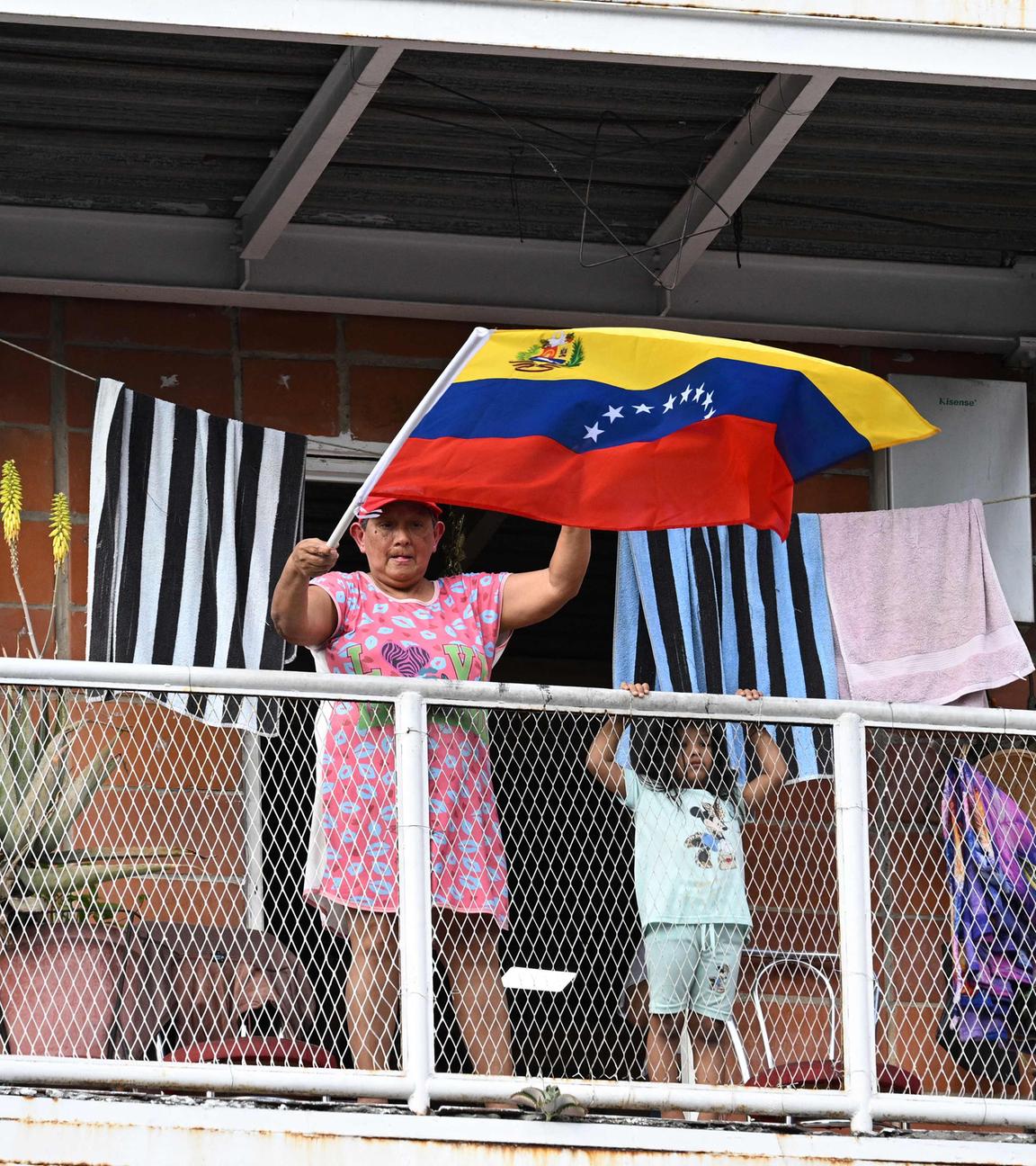 Eine Frau schwenkt eine venezolanische Flagge, während sie vom Balkon aus eine Demonstration junger Chavisten in Caracas am 8. Januar 2026 beobachtet, die die Freilassung des gestürzten venezolanischen Präsidenten Nicolas Maduro und seiner Frau Cilia Flores fordern, die am 3. Januar entführt und nach New York gebracht wurden, um sich dort wegen Drogen- und Waffenhandels vor Gericht zu verantworten.