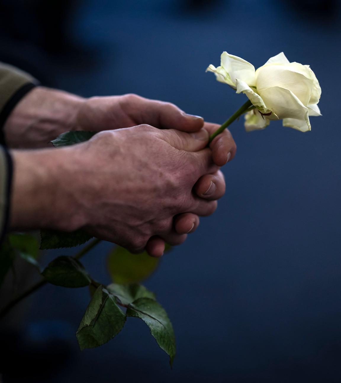 Ein Mitglied des Zivilschutzdienstes hält eine weiße Rose am Ende einer Gedenkfeier für die Opfer des tödlichen Brandes, der in der Silvesternacht die Bar Le Constellation in Crans-Montana erschütterte.