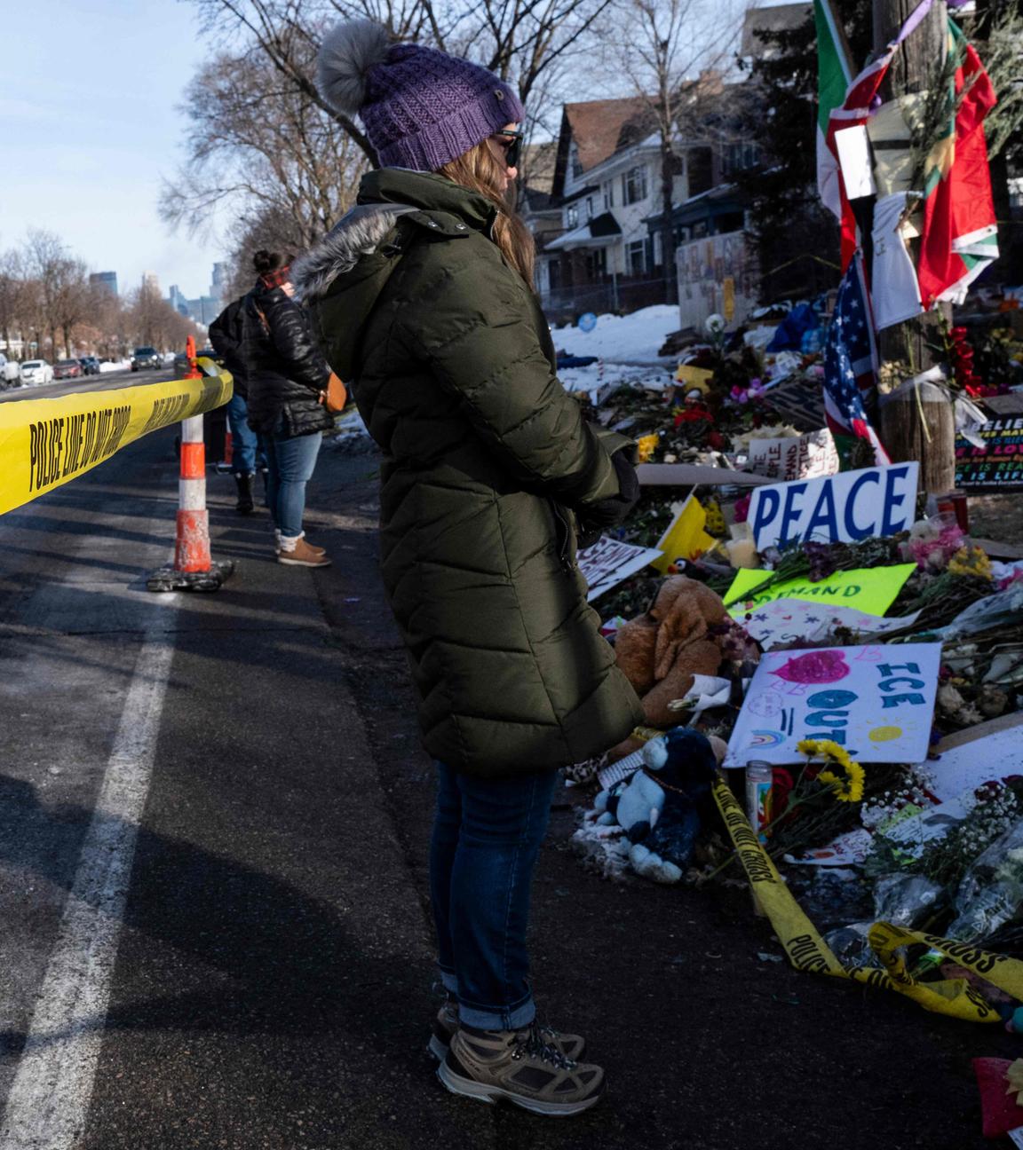 Menschen besuchen stehen an der gedenkstätte von Renee Good. Polizei-Absperrband ist im Vordergrund zu sehen