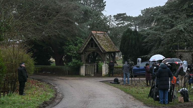 Police (L and C) stand at an entrance to Wood Farm on the royal family's Sandringham Estate as members of the media (R) wait in Norfolk, eastern England on February 19, 2026, where former prince Andrew was arrested earlier in the day. Britain's royal family was in crisis on February 19 as former prince Andrew was in police custody after being arrested on suspicion of misconduct for his links to late US sex offender Jeffrey Epstein.