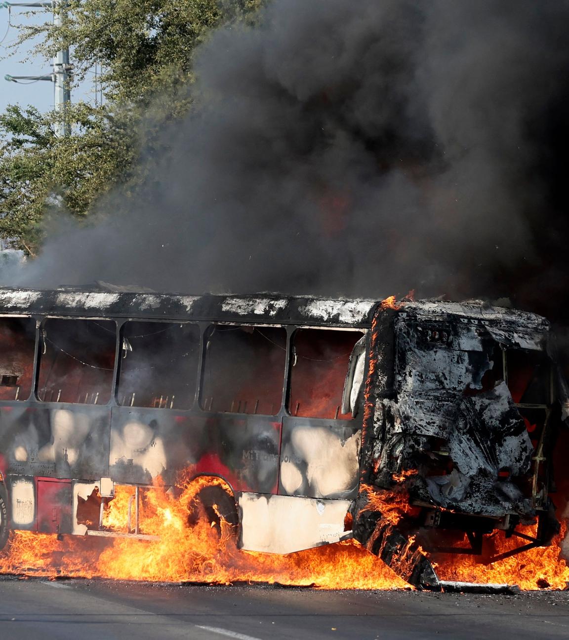 Ein Mitglied der Generalstaatsanwaltschaft steht am 22. Februar 2026 in einer der Hauptstraßen von Zapopan im mexikanischen Bundesstaat Jalisco Wache neben einem Bus, der von organisierten kriminellen Gruppen als Reaktion auf eine Operation in Jalisco zur Festnahme einer hochrangigen Zielperson in Brand gesetzt wurde. Bewaffnete Zivilisten blockierten mehrere Straßen im Bundesstaat Jalisco im Westen Mexikos nach einer Operation der Bundeskräfte in der Stadt Tapalpa, wie lokale Behörden berichteten. Jalisco, wo vier Spiele der bevorstehenden Weltmeisterschaft 2026 ausgetragen werden, ist die Heimat des mächtigen Jalisco New Generation Cartel (CJNG) und wurde in den letzten Jahren von mehreren Gewaltausbrüchen erschüttert