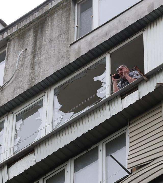 Ein Anwohner telefoniert mit seinem Handy, während er auf dem beschädigten Balkon eines Wohnhauses steht, das bei einem Luftangriff in Odessa am 13. Mai 2026 im Zuge der russischen Invasion in der Ukraine beschädigt wurde.