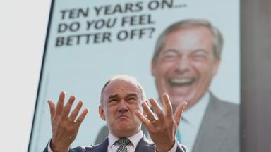 Der Vorsitzende der Liberaldemokraten, Ed Davey, spricht vor einer Plakatwand, auf der der Vorsitzende von Reform UK, Nigel Farage, zu sehen ist, als er am Dienstag, dem 23. Juni, in London eine neue landesweite Plakatkampagne zum 10. Jahrestag des Brexit-Referendums vorstellt,