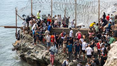 Menschen durchbrechen am Freitag, dem 31. Juli 2026, Stacheldrahtzäune, als sie versuchen, von der nordmarokkanischen Stadt Fnideq in die spanische Enklave Ceuta zu gelangen.