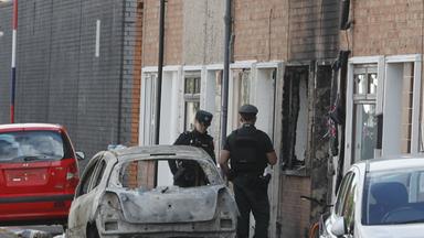 A view of burned-out vehicles and homes on a street as police takes measures in east Belfast, Northern Ireland, on June 10, 2026. Disorder continued across parts of Belfast following a knife attack that left a man seriously injured, with fires reported in several areas of the city during the unrest.