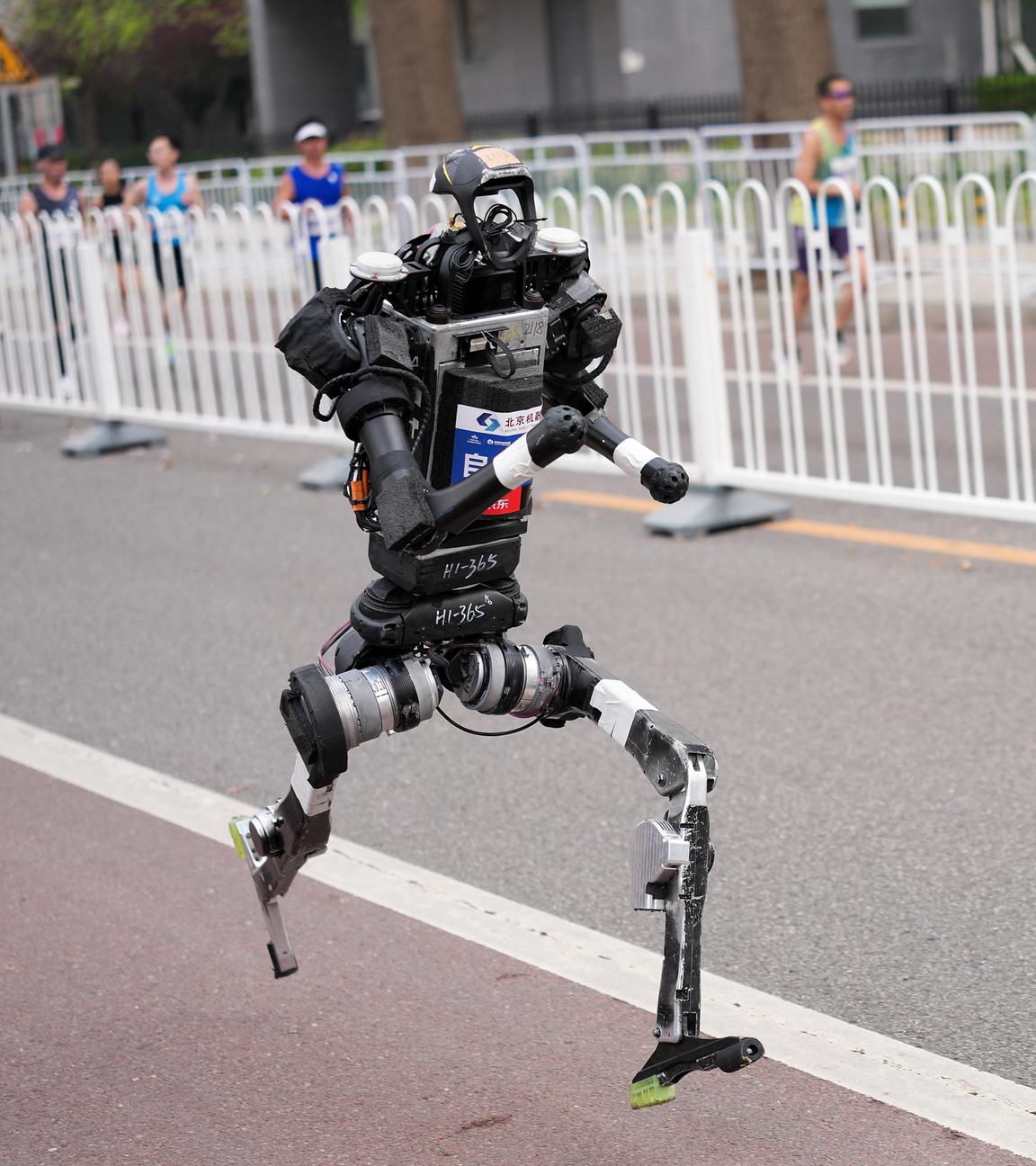 Ein humanoider Roboter tritt bei einem 21-km-Lauf neben Menschen auf einer separaten Bahn in Beijing an