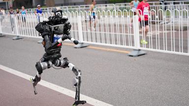 Ein humanoider Roboter tritt bei einem 21-km-Lauf neben Menschen auf einer separaten Bahn in Beijing an