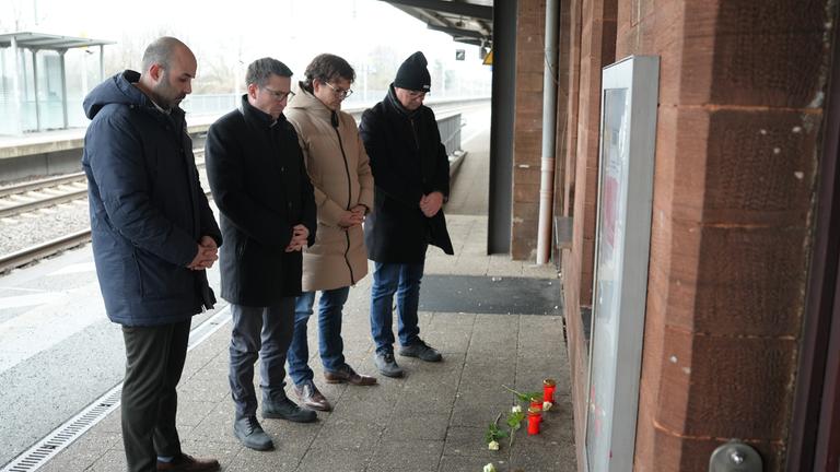 Menschen stehen vor Blumen und Kerzen am Bahnsteig im Gedenken an den Tod eines Zugbegleiters.
