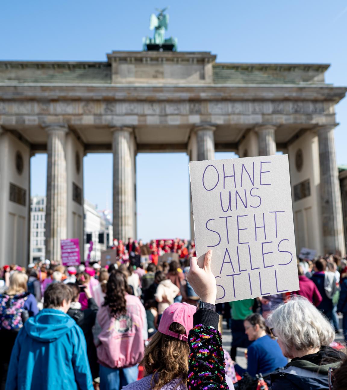 09.03.2026, Berlin: Eine Frau hält beim Aufruf zum weltweiten Frauen-Generalstreik bei einer Demonstration vor dem Brandenburger Tor ein Schild mit der Aufschrift ohne uns steht alles still hoch. Organisiert wir die Demo von einer in Berlin gegründeten Bewegung aus gut Hundert Frauen und einem Dutzend Männern, die für Frauenrechte eintritt