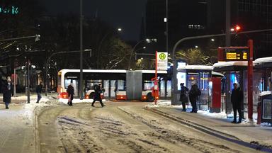 12.01.2026, Hamburg: Passanten warten auf Linienbusse des HVV am frühen Morgen an einer Haltestelle am Dammtor. Eine neue Wetterfront bringt nach der Vorhersage des Deutschen Wetterdienstes (DWD) erst Schnee und dann Regen in den Norden, der auf dem gefrorenen Boden zu gefährlichem Glatteis führen kann.