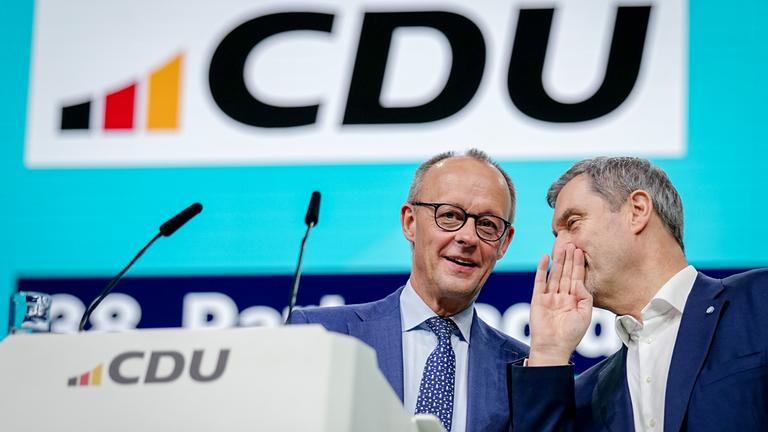 21.02.2026, Baden-Württemberg, Stuttgart: Bundeskanzler Friedrich Merz (l, CDU) und Markus Söder, CSU-Vorsitzender und Ministerpräsident von Bayern, stehen beim CDU-Bundesparteitag auf der Bühne. Nach den Vorstandswahlen geht es am zweiten Tag des Parteitags um die Inhalte. Unter anderem stehen Anträge zu Teilzeit, Einschränkung der Social-Media-Nutzung für Kinder und zur Rentenreform zur Beratung an.