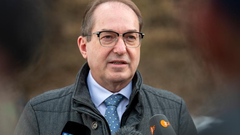 22.02.2026, Bayern, Peißenberg: Bundesinnenminister Alexander Dobrindt (CSU) geht an einer Fernsehkamera vorbei. Er äußerte sich zu den Plänen, Asylbewerber schneller in Arbeit zu bringen.
