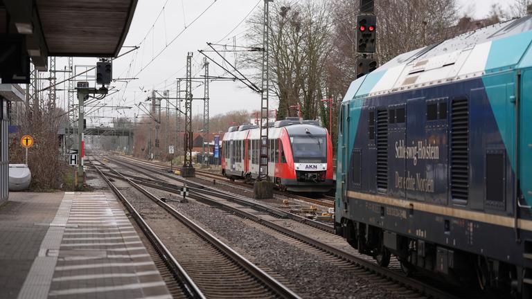 23.02.2026, Schleswig-Holstein, Elmshorn: Eine Regionalbahn der AKN (l) und eine Regionalbahn der Deutschen Bahn (DB) stehen am Bahnsteig vom Bahnhof Elmshorn. Schleswig-Holstein will den Ausbau seiner Schienenprojekte beschleunigen. Dafür plant das Land, das Sondervermögen des Bundes zu nutzen. In den nächsten fünf Jahren sollen so zusätzlich 200 Millionen Euro ins Bahnnetz fließen