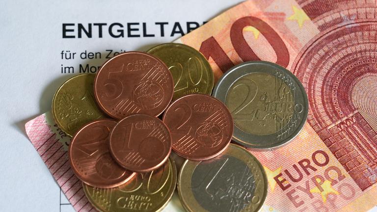 Euro- und Centmünzen liegen auf einem 10-Euro-Schein und bilden den neuen Mindestlohn von 13,90 Euro. 