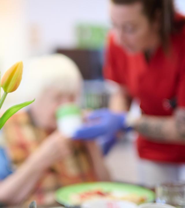 Eine Pflegekraft unterstützt eine Seniorin beim Frühstück im DRK-Pflegezentrum Solferino.