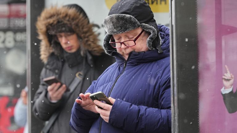 Russland, St. Petersburg: Menschen schauen auf ihre Smartphones an einer Bushaltestelle. Die russische Telekom-Aufsichtsbehörde Roskomnadsor hat weitere Beschränkungen gegen verschiedene Messenger-Dienste angekündigt, darunter auch Telegram.