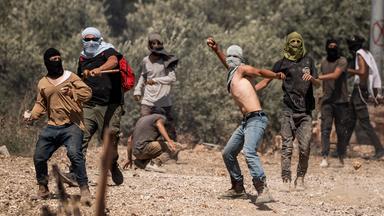 Israelische Siedler werfen Steine während eines Angriffs im Westjordanland.