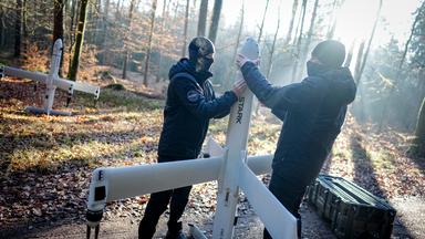 Mitarbeiter der Firma Stark Defence, die nicht erkannt werden möchten, demonstrieren in einem Waldstück in der Nähe des Sprengplatzes den Aufbau ihrer Drohnenwaffe «Virtus». Eine Kamikaze-Drohne, die auch Loitering Munition (lauernde Munition) genannt wird, dieses Typs wurde später mit einem Gefechtskopf des Herstellers TDW erfolgreich auf dem Sprengplatz des Rüstungsunternehmens MBDA in Bayern getestet. Die Hersteller Stark und TDW haben den ersten scharfen Schuss einer deutschen Loitering Munition demonstriert und die Wirkung auf Panzerstahl untersucht.