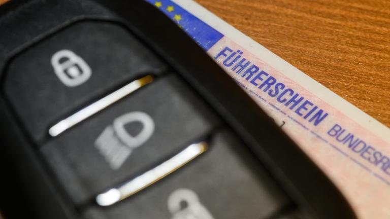 ILLUSTRATION - 26.01.2026, Sachsen, Dresden: Ein Führerschein liegt unter einem Autoschlüssel.