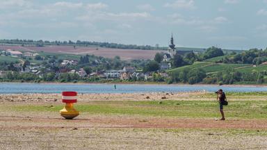 Rheinland-Pfalz, Nierstein: Ein Mann fotografiert bei Niedrigwasser ein Fahrwasserzeichen (Fluss-Boje). Der Rhein ist bei Nierstein aufgrund des Niedrigwassers sehr stark zurückgegangen.