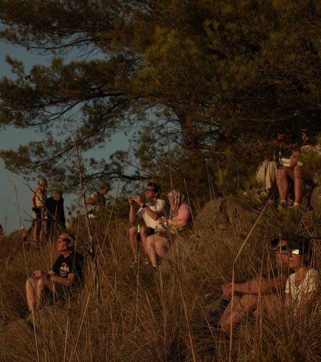 Menschen beobachten den Himmel mit speziellen Brillen, während sie in Solier auf die Sonnenfinsternis warten.