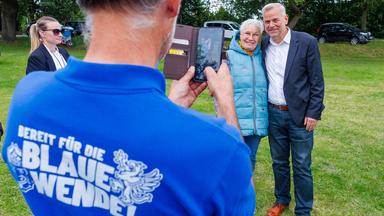 17.09.2026, Mecklenburg-Vorpommern, Boizenburg: Leif-Erik Holm (r), Spitzenkandidat der AfD für die Landtagswahl in Mecklenburg-Vorpommern, lässt sich mit einer Besucherin des Bürgerfestes der Partei auf der Ziegenwiese fotografieren. Am 20.09.2026 wird in Mecklenburg-Vorpommern ein neuer Landtag gewählt. Foto: Jens Büttner/dpa