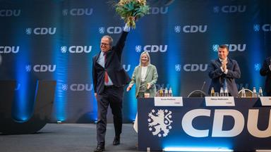Mario Voigt (CDU, l), Ministerpräsident von Thüringen, winkt nach seiner Wiederwahl zum Landesvorsitzenden der CDU Thüringen mit einem Blumenstrauß